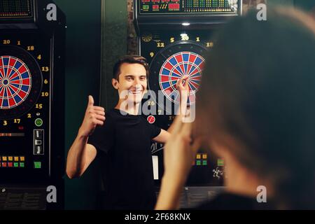 Darts. Junge Menschen werfen Darts auf das Ziel. Freundliches Spiel in einem Pub. Stockfoto