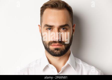 Emotionen und Menschen Konzept. Kopfschuss von ernst aussehenden schönen Mann mit Bart, sieht zuversichtlich und entschlossen, weißen Hintergrund Stockfoto
