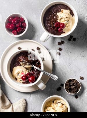 Lecker, schmilzt im Mund veganer Schokoladenbrownie in einem Becher mit warmen Kirschen und veganer Vanilleeis. Perfektes kleines Vergnügen am Nachmittag. Stockfoto