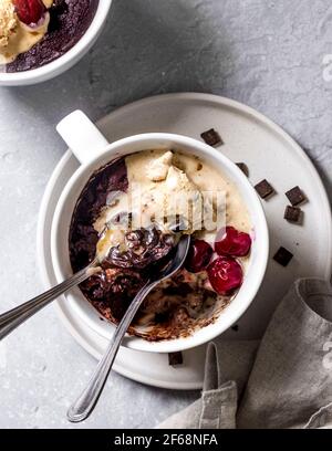 Lecker, schmilzt im Mund veganer Schokoladenbrownie in einem Becher mit warmen Kirschen und veganer Vanilleeis. Perfektes kleines Vergnügen am Nachmittag. Stockfoto