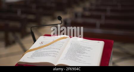 Detail eines Rednerpultes aus Marmor mit rotem Filz und Eine bibel mit einigen Bänken im Hintergrund in einem kirche Stockfoto