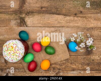 Osterkuchen und bemalte Eier auf einem hölzernen Hintergrund. Stockfoto