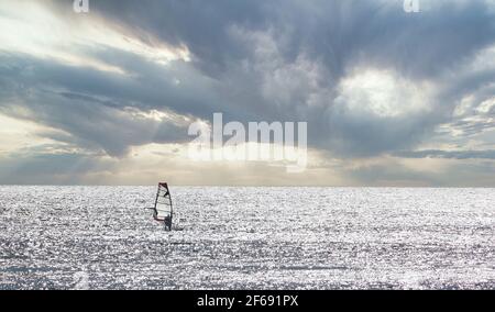 Silhouette einer Person, die an einem stürmischen Nachmittag Windsurfen praktiziert Stockfoto