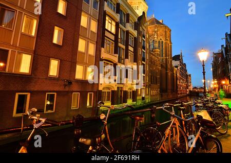 Fahrräder auf dem Kanal in Amsterdam, Niederlande bei Nacht von bunten Lichtern beleuchtet. Nacht. Bicykle Stockfoto