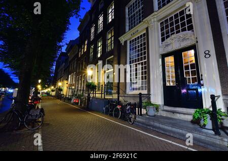 Fahrräder auf dem Kanal in Amsterdam, Niederlande bei Nacht von bunten Lichtern beleuchtet. Nacht. Bicykle Stockfoto