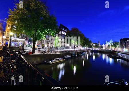 Fahrräder auf dem Kanal in Amsterdam, Niederlande bei Nacht von bunten Lichtern beleuchtet. Nacht. Bicykle Stockfoto