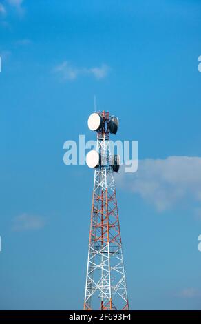 Telekommunikationsturm mit Antennen auf einem Hintergrund von blauem Himmel und Wolken. Intelligente Antennen übertragen 4G und 5G Mobilfunksignale an Verbraucher. Stockfoto