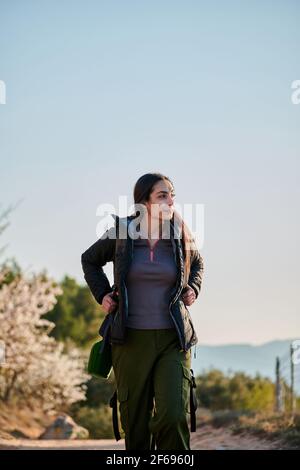 Eine Forscherin spaziert auf einem unbefestigten Weg und beobachtet die Natur Stockfoto