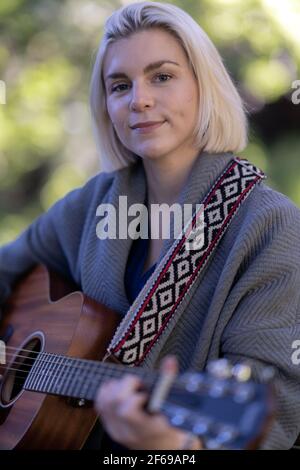 Schöne junge Frau spielt Gitarre in Redwood Hain Stockfoto