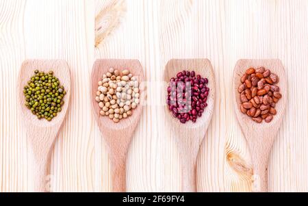 Auswahl an Bohnen und Linsen in Löffel aus Holz auf Holz- Hintergrund. Soja, mung Bean, roten Bohnen und Braun pinto Bohnen. Stockfoto