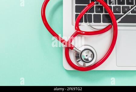 Nahaufnahme des roten Stethoskops von oben auf der Laptop-Tastatur. Konzept von Medizin und Technik Stockfoto