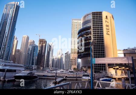 Panoramablick auf die schönen Pier 7 Restaurants im luxuriösen Touristenviertel von Dubai Marina mit Marina Mall und Kanal mit Yachten im Hintergrund. Stockfoto