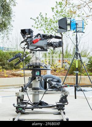 Professionelle Ausrüstung zum Filmen von Fernsehsendungen und Filmen. Eine Videokamera auf Stativ und Beleuchtungsgerät. Stockfoto