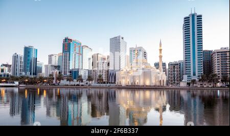 Januar 2021, Sharjah, VAE. Panoramablick auf die wunderschön beleuchtete Al Noor Moschee während der frühen Sonnenaufgangsstunden, die Reflexionen im Wasser zeigt Stockfoto