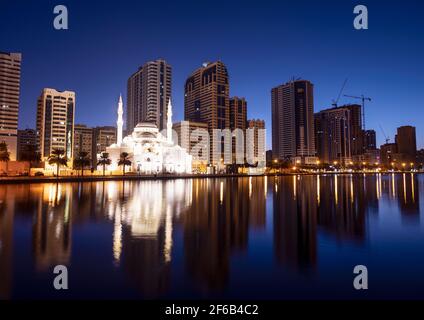 Januar 2021, Sharjah, VAE. Panoramablick auf die wunderschön beleuchtete Al Noor Moschee während der frühen Sonnenaufgangsstunden, die Reflexionen im Wasser zeigt Stockfoto