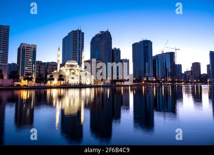 Januar 2021, Sharjah, VAE. Panoramablick auf die wunderschön beleuchtete Al Noor Moschee während der frühen Sonnenaufgangsstunden, die Reflexionen im Wasser zeigt Stockfoto