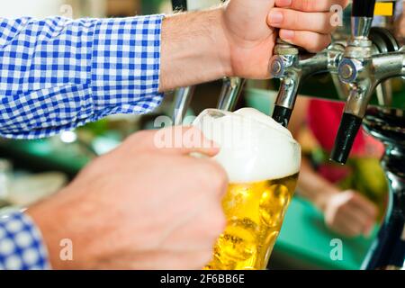 Mann ein Bier vom Hahn auf einem Kegerator im Pub oder Inn zeichnen Stockfoto