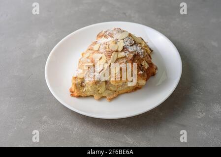 Mandelcroissant auf dem Teller mit Puderzucker Stockfoto