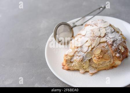 Mandelcroissant auf dem Teller mit Puderzucker Stockfoto