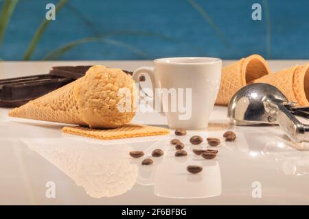 Köstlicher Eiskegel mit einer Tasse Kaffee, einer Eislöffel und Kaffeebohnen auf einem unscharfen Hintergrund: Selektiver Fokus. Eiscreme-Konzept. Stockfoto
