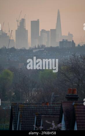 Wimbledon, London, Großbritannien. 31. März 2021. Heller Morgennebel bei einem Blick über die flachen Hausdächer der Vorstadt auf ferne Wolkenkratzer und Baukräne in der City of London vor einem weiteren Sonnentag in der Hauptstadt. Quelle: Malcolm Park/Alamy Live News Stockfoto