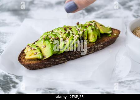 Gesunde Avocado Toast auf Beton Hintergrund. Vollkornbrot, Sesamflachskerne. Vegane Keto-Diät. Gesunde Ernährung. Trendiges Guacamole-Sandwich Stockfoto