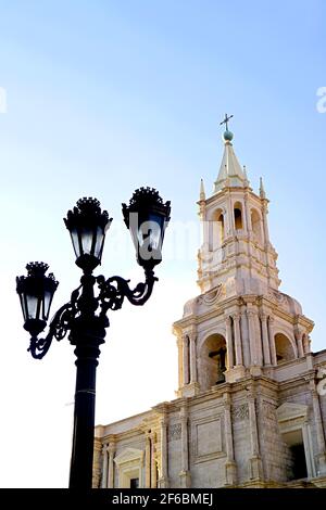 Wunderschöner Glockenturm aus weißem vulkanischem Stein der Basilica Cathedral of Arequipa mit Vintage-Lamppost aus schwarzem Eisen, Arequipa, Peru Stockfoto