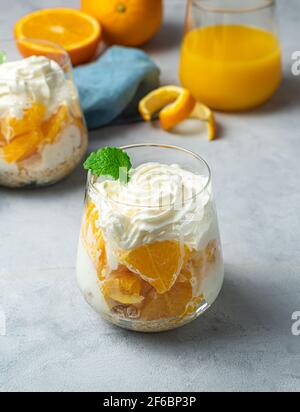 Fruchtdessert mit Orange, Creme und Müsli. Vertikale Ansicht. Stockfoto