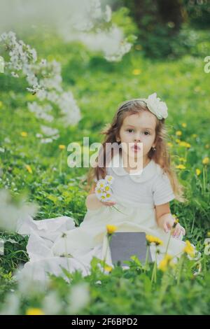 Mädchen im Kleid hält Strauß von weißen Gänseblümchen in der Kirschgarten im Frühling Stockfoto