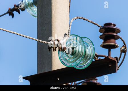 Elektrischer Pol gegen den blauen klaren Himmel. Dreiphasige Stromleitung zum Drehen. Stockfoto
