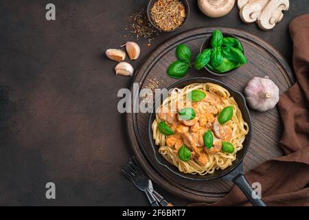 Pasta mit Knoblauch-Pilz-Sauce und Basilikum auf dem Hintergrund der Zutaten. Stockfoto