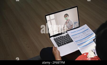 Ältere Patientinnen, die mit einem Laptop auf dem Sofa sitzen und einen Videoanruf mit einem Online-Arzt führen und eine professionelle Gesundheitsberatung erhalten. Stockfoto