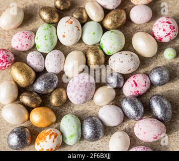 Bunte Bonbons geformte Eier auf einem hellen Beton Hintergrund. Frohe Ostern. Minimalismus-Konzept. Selektiver Fokus. Draufsicht. Nahaufnahme. Stockfoto