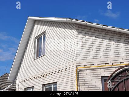 Neues weißes Ziegelhaus mit einer Nahaufnahme von Problembereichen für Regenrinnen-Abdichtung. Stockfoto