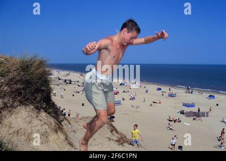 Ein Teenager, der von einer Sanddüne am Hemsby Beach in der Nähe von Great Yarmouth springt. Norfolk. England. VEREINIGTES KÖNIGREICH Stockfoto