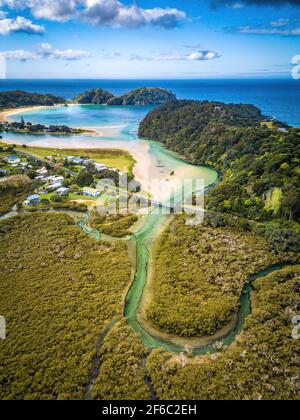 Drohnenansicht des türkisfarbenen Flusses, der sich zwischen Bäumen schlängelt und zum Meer führt. Luftaufnahme von Neuseeland fantastische Landschaften und Landschaften. Stockfoto