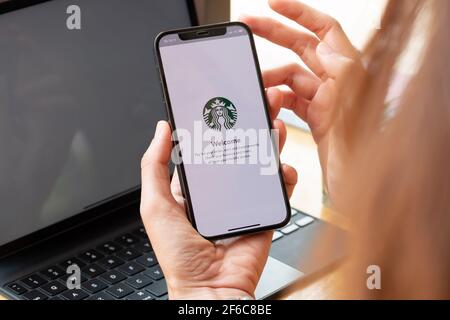 Chiang Mai, Thailand : Mär 7 2021 : EINE Frau hält iPhone 12 mit Starbucks Logo auf dem Bildschirm in Starbucks Coffee Shop. Stockfoto