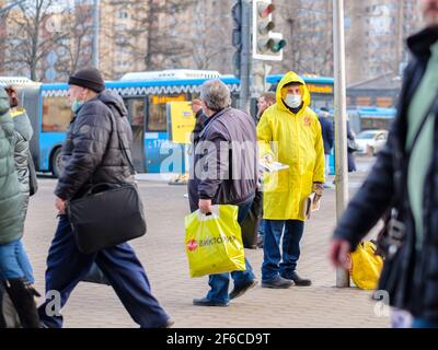 Moskau. Russland. März 26, 2021. Ein Mann in einem gelben Regenmantel und einer medizinischen Maske verteilt politische Propagandazeitungen an die Passanten Stockfoto