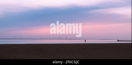 Ein eineinziger Iron man am Crosby Beach in der Nähe von Liverpool, gesehen im März 2021 in der Abenddämmerung. Dies ist eine der hundert Statuen, aus denen die Kunstinstallation besteht Stockfoto