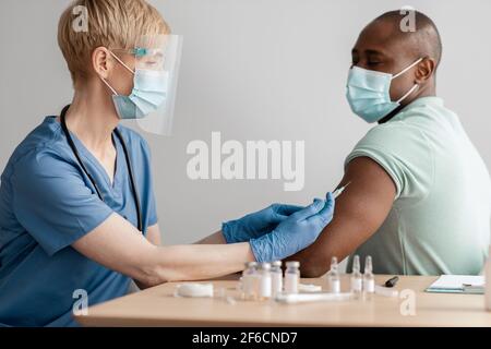 Zentrumsimpfung gegen Covid-19. Krankenschwester, Erwachsene Frau, Arzt Stockfoto