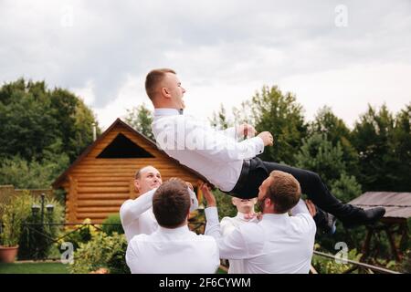 Stilvoller Groomsman mit dem Bräutigam, der auf dem Hinterhof steht und sich auf die Hochzeitszeremonie vorbereitet. Freund verbringt draußen Zeit miteinander Stockfoto