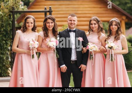 Hübscher Bräutigam steht neben schöner Brautjungfer mit Blumensträußen Stockfoto