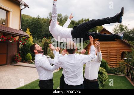 Stilvoller Groomsman mit dem Bräutigam, der auf dem Hinterhof steht und sich auf die Hochzeitszeremonie vorbereitet. Freund verbringt draußen Zeit miteinander Stockfoto