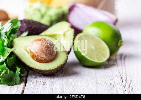 Zutaten für Guacamole-Sauce Avocado, rote Zwiebeln, Koriander, Limette auf rustikalem Holztisch. Zubereitung von Speisen Stockfoto