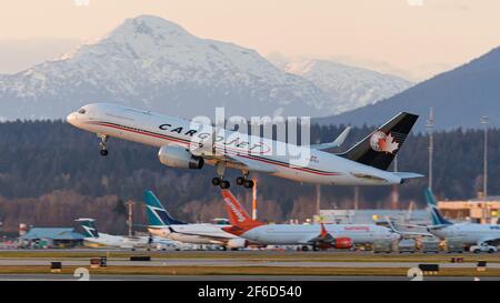 Richmond, British Columbia, Kanada. März 2021, 29th. Am Montag, den 29. März 2021, hebt ein Cargojet Boeing 757 (C-GTCJ) bei Sonnenuntergang vom Vancouver International Airport, Richmond, B.C. ab. Im Hintergrund sind WestJet- und Sunwing Boeing 737-Jets am Inlandsterminal des Flughafens zu sehen. Quelle: Bayne Stanley/ZUMA Wire/Alamy Live News Stockfoto