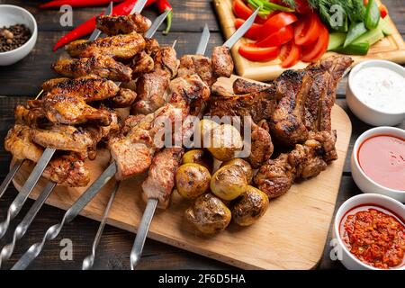 Verschiedene leckere gegrillte Fleisch auf Spieße mit frischem Gemüse und Gebackene Kartoffeln Stockfoto
