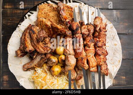 Verschiedene leckere gegrillte Fleisch auf Spieße mit frischem Gemüse und Gebackene Kartoffeln Stockfoto