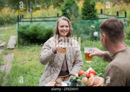 Ein Ehepaar feiert den Kauf von Immobilien, auf dem Land. Ein Mädchen und ein Kerl sitzen an einem Picknicktisch und klicken Bierbecher. Stockfoto