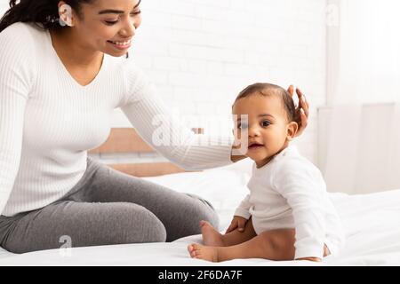 Afrikanische Mama Streichelte Kleines Baby Auf Kopf Sitzend Im Schlafzimmer Stockfoto