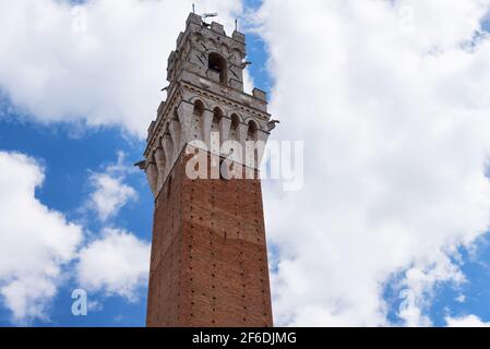 Detail des Torre del Mangia 87 m. Turm von Mangia am blauen Himmel mit Wolken. Siena, Italien Stockfoto